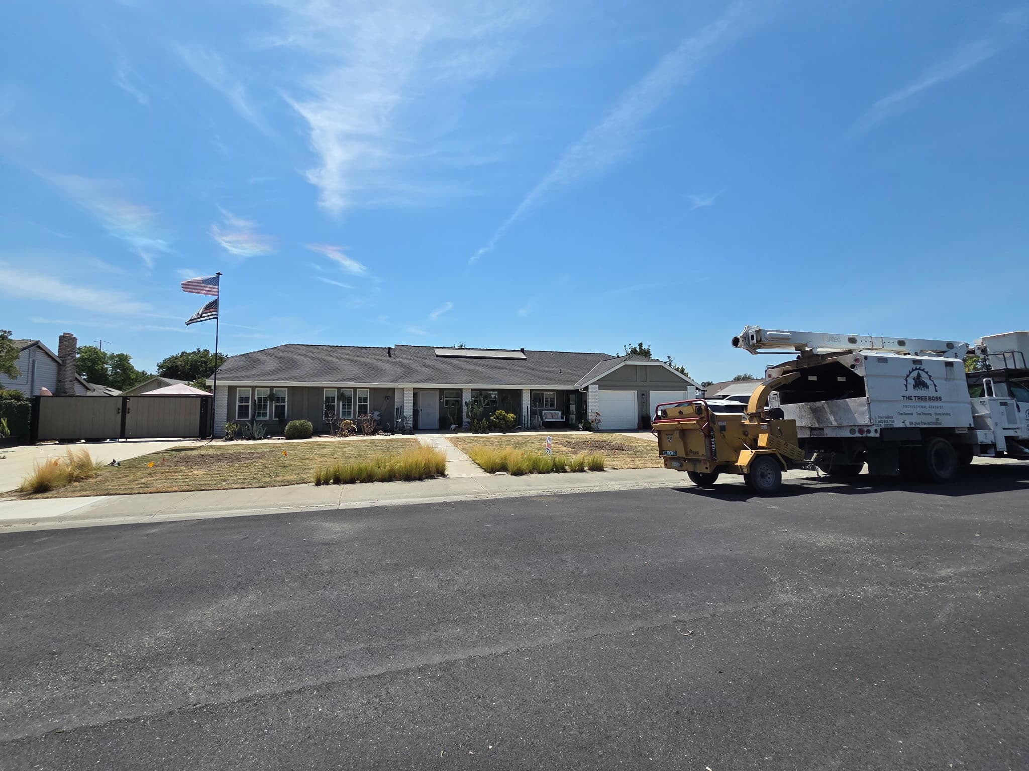 Chipper and bucket truck at the curb after a front-yard removal